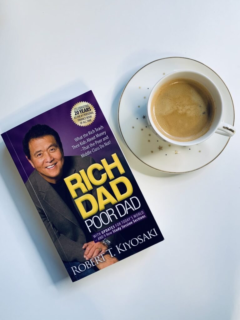 rich dad poor dad book next to a cup of coffee about to be read