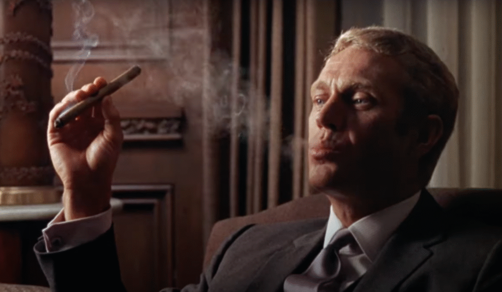 Screenshot from The Thomas Crown Affair (1968) showing Steve McQueen smoking a cigar